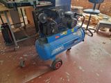 a blue air compressor sitting on a cart in a workshop