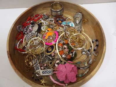 un bol en bois rempli de nombreux bijoux, posé sur une table