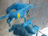 three blue horses that are on display in a glass case