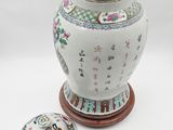 a vase with a lid sitting on a table next to a plate