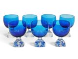 six verres à pied bleus sont alignés en rangée