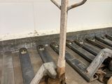 a dolly with a handle on it next to a pile of pallets
