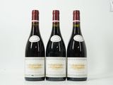 trois bouteilles de vin rouge sont alignées sur une surface blanche