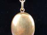a close up of a necklace with a gold pendant on a black background