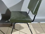 a green chair and a black chair on a tiled floor
