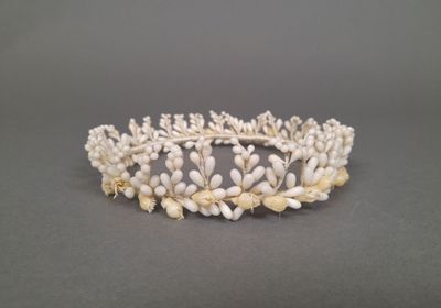 un gros plan d'une couronne ornée de perles blanches sur une surface grise