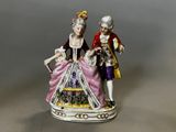 two figurines of a man and a woman dressed in period clothing