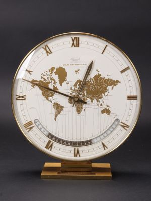 une image représentant une horloge dorée et blanche sur laquelle figure une carte du monde