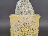 a yellow vase with a bird sitting on top of it
