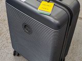 une valise posée sur le trottoir, sur laquelle est collé un autocollant