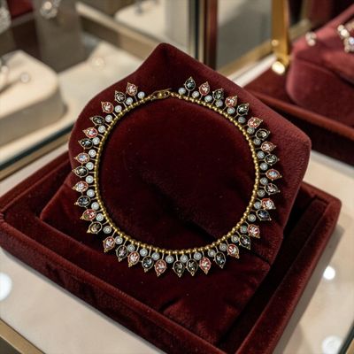 deux coffrets en velours rouge sur lesquels est posé un collier en or et diamants
