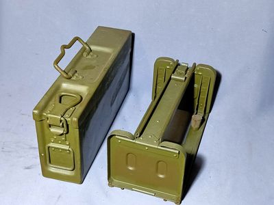 two army green boxes sitting next to each other on a white surface