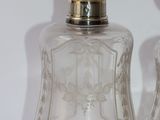 two clear glass bottles with silver lids on a white surface