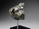 une tête de chien en bronze posée sur un socle noir