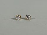 a pair of diamond stud earrings on a white surface
