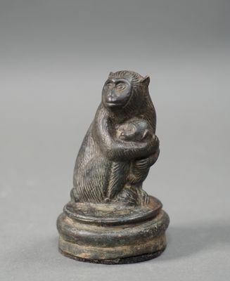 an old bronze figurine of a monkey holding a baby