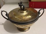 a gold colored bowl with a lid on a white table