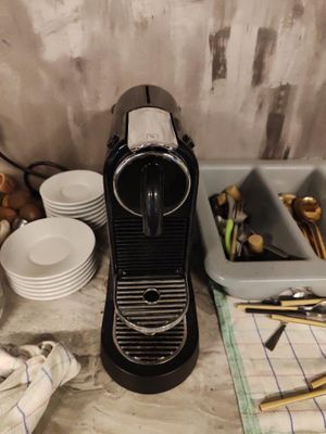 une cafetière posée sur un plan de travail, à côté d'assiettes et de tasses