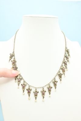 an image of a person holding a necklace on a mannequin
