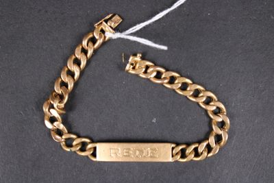 a close up of a gold chain bracelet with a tag on it