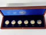 four gold coins in a wooden box with a blue cover