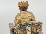 statue of a man sitting on a bench with a hat on top of his head