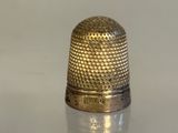 a gold thimble sitting on a white surface