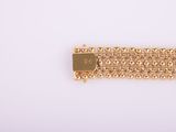 a close up of a gold bracelet on a white surface