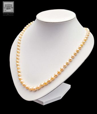 un collier blanc orné de perles posé sur un présentoir pour mannequin