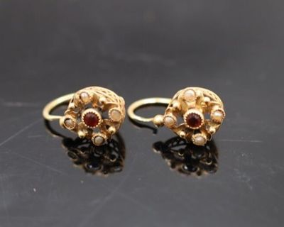 paire de boucles d'oreilles en or ornées de grenats sur fond noir