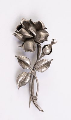 une broche en forme de fleur argentée sur un fond blanc