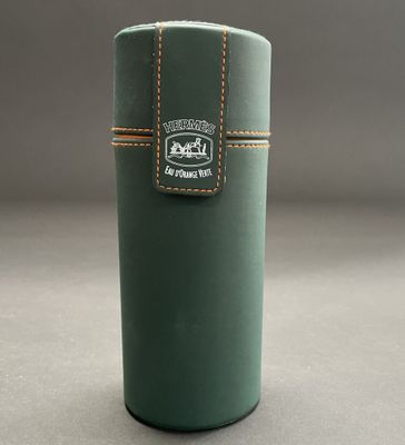 the green cylinder is holding a leather case with a logo on it
