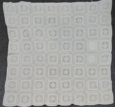 une couverture blanche au crochet posée sur une surface noire