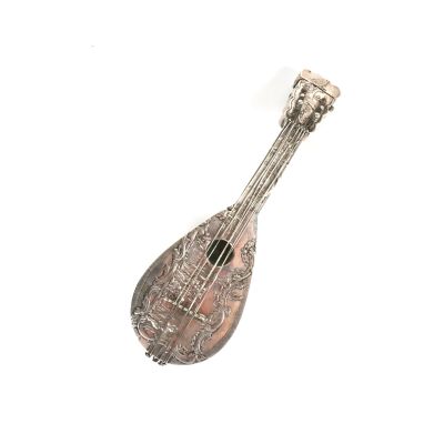 instrument de musique plaqué argent posé sur une surface blanche, avec un fond blanc