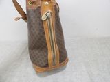 brown and tan handbag sitting on a white surface with a white background