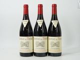 three bottles of red wine sitting on top of a white table