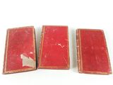 three red books sitting on top of each other on a white surface