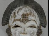 un masque blanc surmonté d'un oiseau