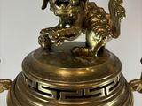a golden dog statue on top of a brass urn