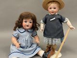 deux poupées en porcelaine représentant un garçon et une fille assis l'un à côté de l'autre
