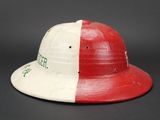 an old red and white baseball helmet with a green and white stripe on it