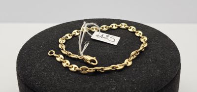 un gros plan d'un bracelet à chaîne dorée posé sur un écrin noir