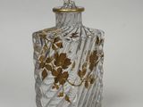 une image représentant une bouteille en verre ornée de fleurs dorées