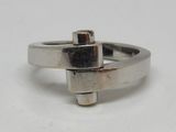 bague en argent ornée d'une croix au centre, sur un fond blanc