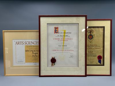 Trois certificats encadrés, de tailles et de formes variées, sont exposés sur un fond bleu.