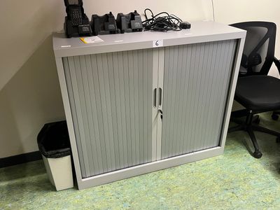 une armoire blanche avec une porte et une chaise noire à côté