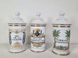 three white and gold canisters sitting on top of a white table
