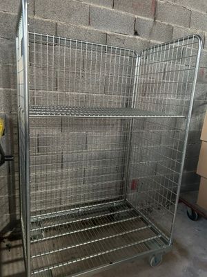 une grande cage métallique munie de roues, dans une pièce
