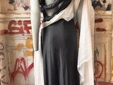 a mannequin wearing a black and white dress in front of a wall with graffiti