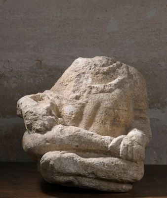 une sculpture en pierre posée sur une table en bois, à côté d'un vase